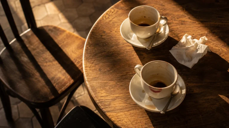 Duas xícaras usadas sobre mesa com uma cadeira afastada — sonhar com pessoa conhecida