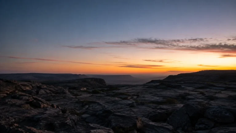 Paisagem rochosa escura ao amanhecer com luz surgindo no horizonte — sonhar com inferno