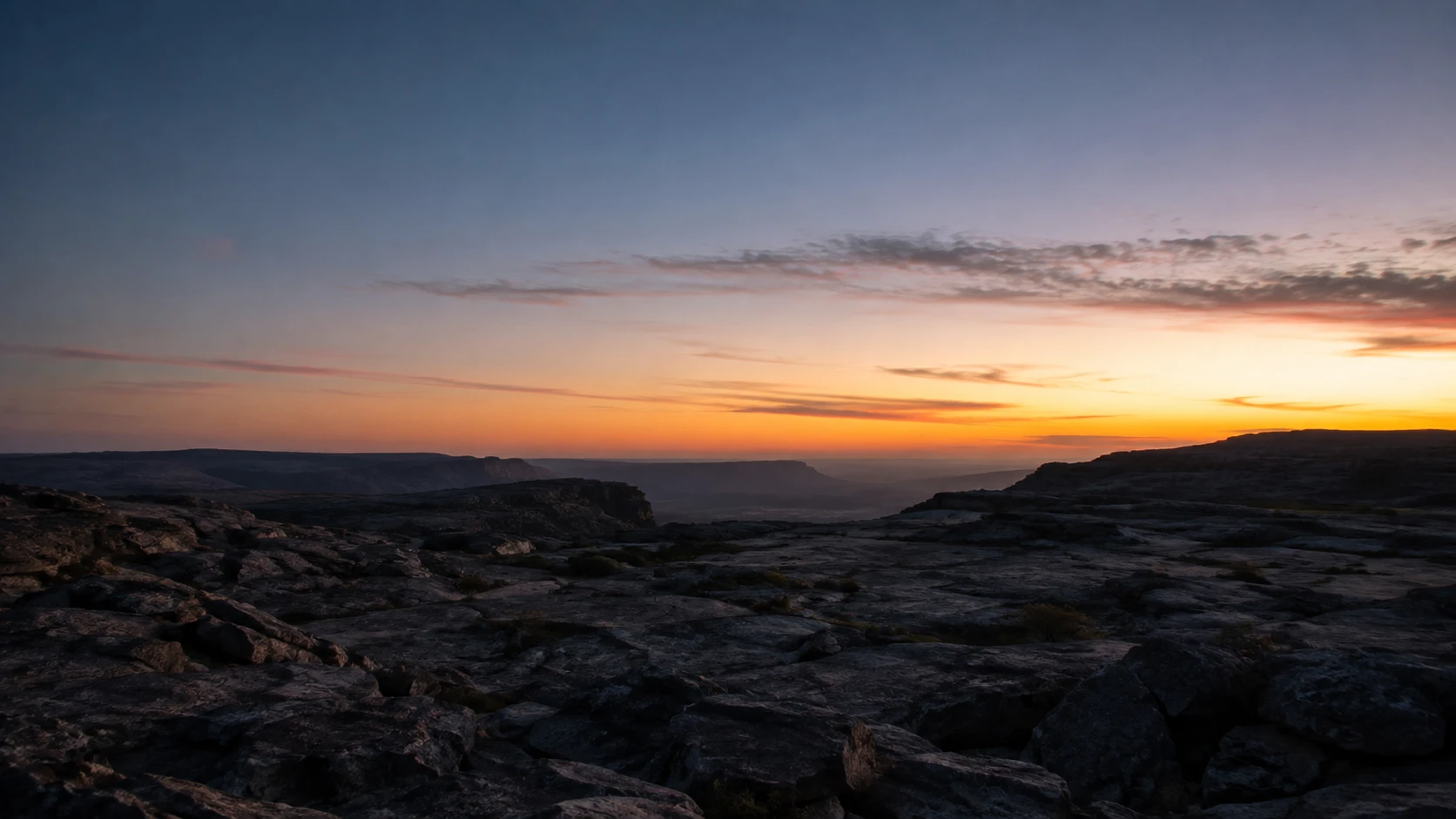 Paisagem rochosa escura ao amanhecer com luz surgindo no horizonte — sonhar com inferno